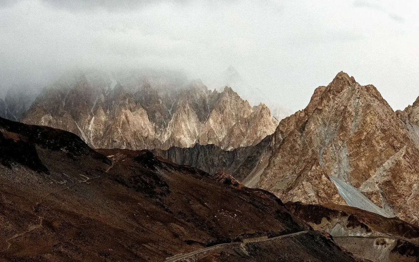 Cloud-wrapped crags above a gorge road in the mountains of the north